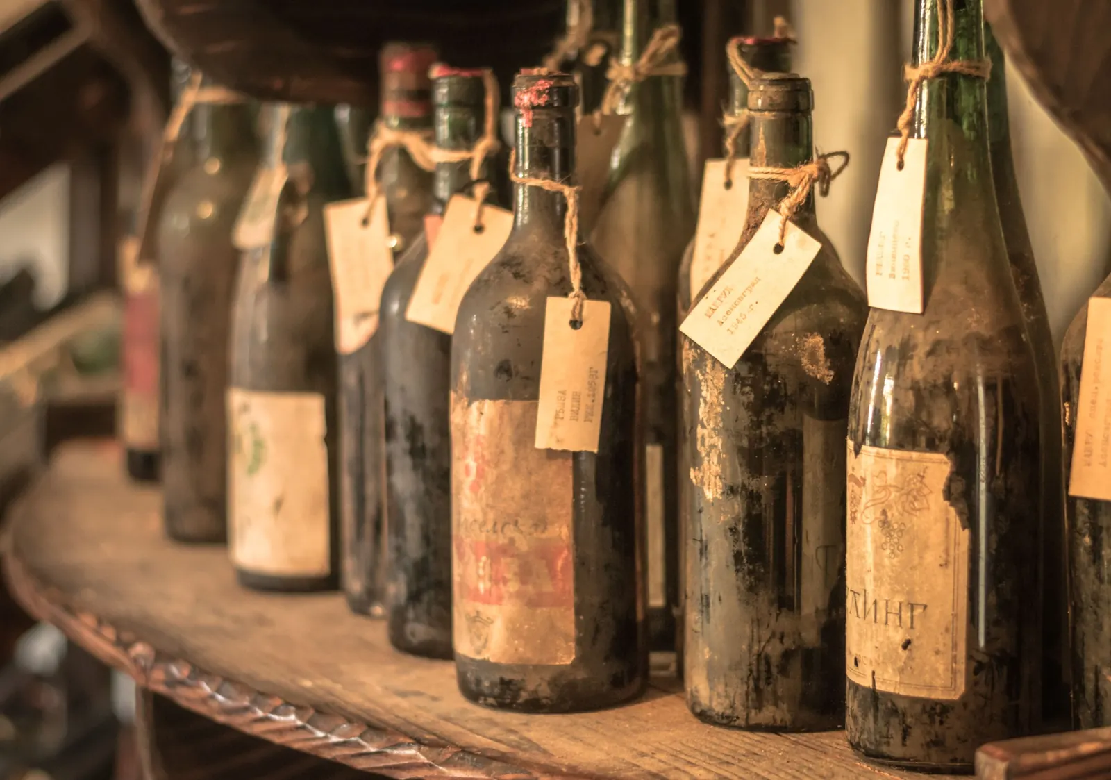 Old dusty wine bottles on a wooden shelf